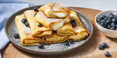 blueberry crepes on a plate with powdered sugar and fresh blueberries