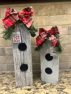 two wooden birdhouses decorated with red and black bows