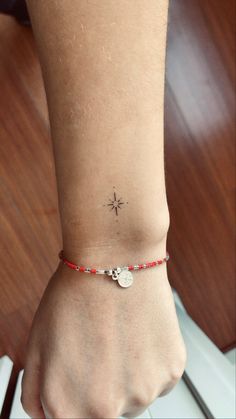 a woman's foot with a small star tattoo on her left ankle and red beaded bracelet