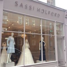 mannequins are displayed in the window of a dress shop, which sells wedding gowns