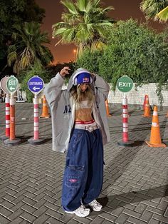 a woman standing in front of orange and white traffic cones with her hands up to her head