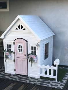 a pink and white doll house with flowers on the door