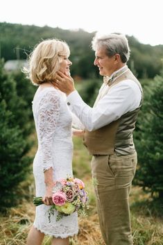 an older man and woman standing next to each other in front of some christmas trees