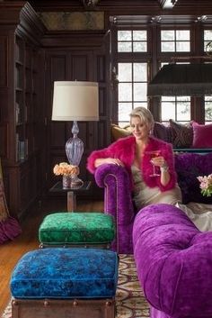 a woman sitting on a couch in a living room with purple furniture and green pillows