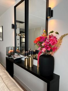 a vase filled with flowers sitting on top of a black table next to a mirror