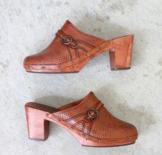 "1970s Leather and wood wedges in size 5-1/2. Slip on style with full leather lining. Squared toe and contrast stitching in dark brown. Buckle detail. Perforated pattern. Genuine wood heel and soles. Genuine leather in an antiqued cognac color. In excellent vintage condition with just one split in the wood heel (this does not seem to be a stability issue for the shoes). Brand: Thom McAn // Woodworks Made in Brazil Size: None Listed; Recommending a size 5-1/2. FOR REFERENCE: I wear a size 6-1/2 t Leather And Wood, Clogs And Mules, Cognac Color, Wood Heel, Shoes Brand, Clogs Shoes, Short Boots, Vintage Shoes, Lace Boots