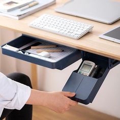 a person holding a cell phone under a desk