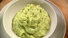 a white bowl filled with guacamole on top of a wooden table