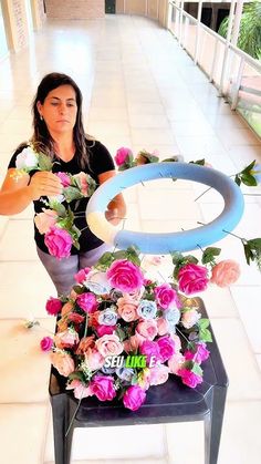 a woman sitting on a chair with flowers in front of her and an object that looks like a ring