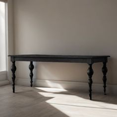 an empty room with a wooden table in the corner and sunlight coming through the window