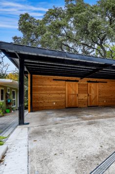 two garages with wooden doors in front of them and trees on the other side