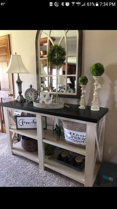 a white and black console table with mirrors on it's sides in a living room