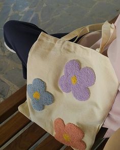 a woman is sitting on a bench with a flowered bag in front of her