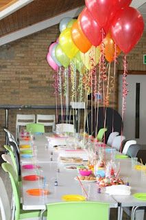 a long table with many balloons and confetti on it