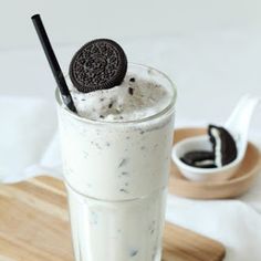 an oreo cookie and milkshake in a glass on top of a cutting board