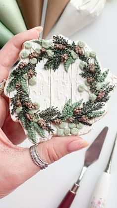 a person holding a christmas wreath cookie in their hand