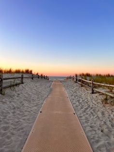 a wooden walkway leading to the beach at sunset