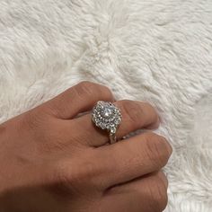 a woman's hand with a diamond ring on top of white furnishing