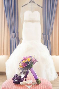 a bouquet of flowers sits on top of a stool in front of a wedding dress