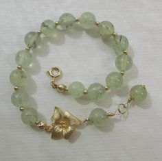 This floral bracelet is interestingly styled, and will go with casual wardrobe and elegant formal attire. The round natural stones of light green rutilated tourmaline quartz measure approximately 8.5 mm in diameter, semi-transparent with some of the typical streaky dark green moss inclusions and mottles. They are organic, somewhat rustic-looking stones, with some very slight hollows/dents, stone veins and spots. Each of these natural stones is always grained and mottled differently, therefore ea Tourmaline Quartz, Floral Bracelet, Flower Leaf, Hibiscus Flower, Beading Wire, Leaf Charms, Quartz Bracelet, Small Pendant, Gifts For Nature Lovers