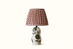 a table lamp with a red and white flower design on the base, next to a light shade