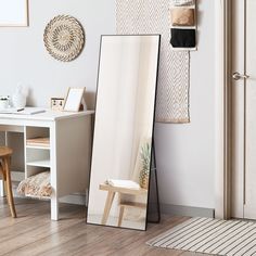 a mirror sitting on top of a wooden floor next to a white table and chair