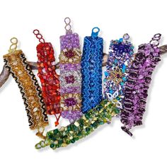 several different colored bracelets hanging from a tree branch