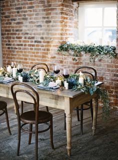 the table is set with candles, greenery and wine glasses for dinner guests to enjoy