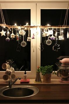 a kitchen sink sitting under a window covered in lights