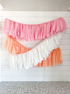 three tiered ruffles hanging on the wall in front of a white and pink wall