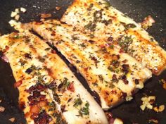 two pieces of fish sitting on top of a pan covered in sauce and seasoning