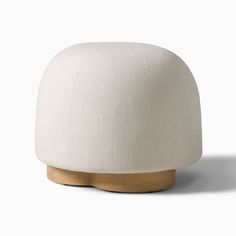 a white ottoman sitting on top of a wooden base