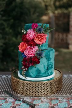 a three tiered blue cake with flowers on top