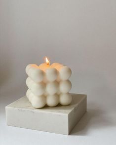 a white candle sitting on top of a square block