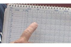 a hand pointing at a baseball score book