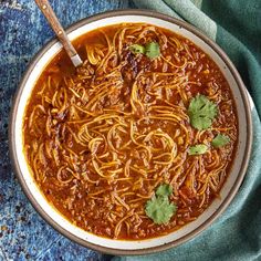 a bowl filled with chili and noodles on top of a blue towel