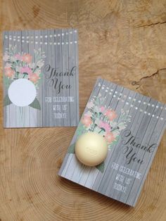 two cards with flowers on them are next to a candle