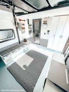 the interior of an rv with white walls and black rugs on the floor,