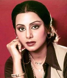 the woman is posing with her hand on her chin and wearing a black shirt, silver necklace and bracelet