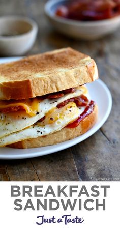 a breakfast sandwich on a white plate with bacon and eggs in the middle, sitting on a wooden table