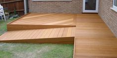 a wooden deck with steps leading up to the back door and patio area in the background