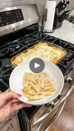 a person is holding a plate with pasta on it in front of the stove top