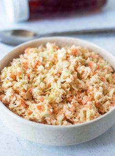 a bowl filled with coleslaw and carrots on top of a white table