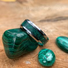 two green rings sitting next to each other on top of a wooden table with rocks