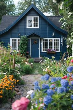 a blue house surrounded by flowers and trees