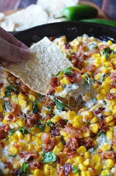 a tortilla topped with corn and cheese being held by a tortilla chip