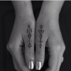 two hands holding each other with tattoos on their fingers and one has an arrow in the middle