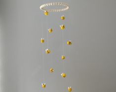 a white and yellow mobile with bees hanging from it's sides in a room