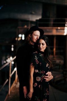 a man and woman standing next to each other in front of a building at night