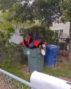 the trash can is full of garbage and there are two stuffed animals in it's bins